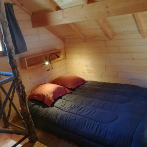 Cabane en bois cosy avec lit douillet et murs en bois naturel.