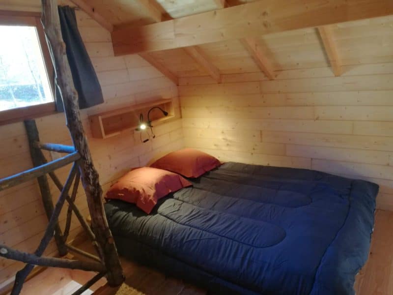 Chalet en bois cosy avec lit double et décoration chaleureuse.