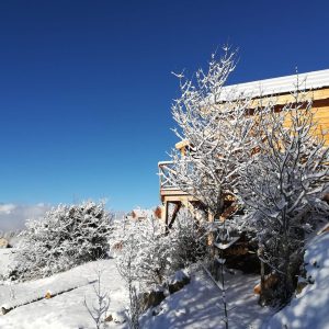 Chalet en bois enneigé, entouré de paysages montagneux à couper le souffle.