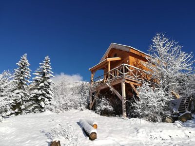 Cabane sur pilotis en bois, entourée de neige et de sapins en Provence-Alpes-Côte dAzur.