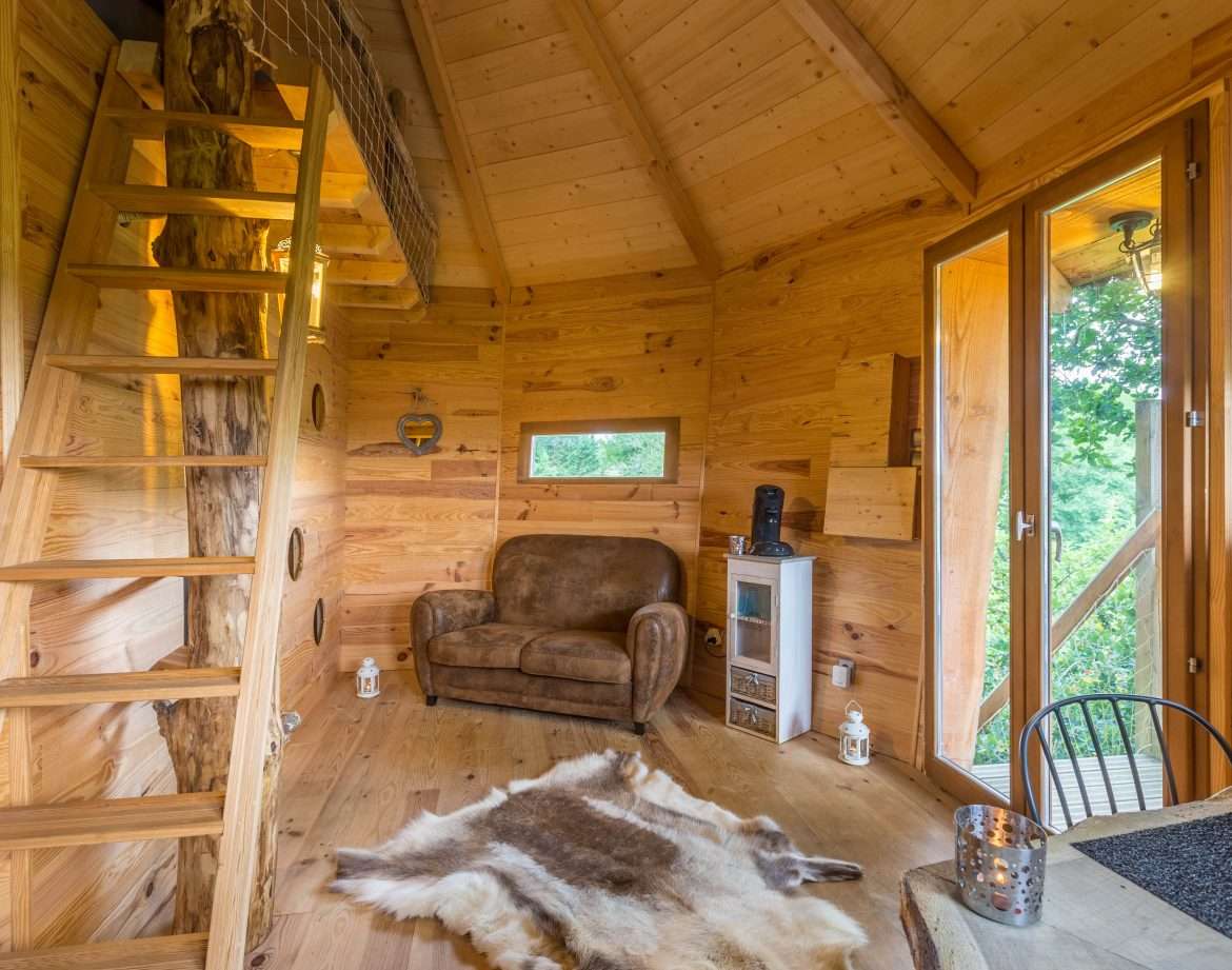 Cabane en bois dans les Midi-Pyrénées, avec un escalier en bois et un coin salon cosy.