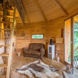 Cabane en bois dans les Midi-Pyrénées, avec un escalier en bois et un coin salon cosy.