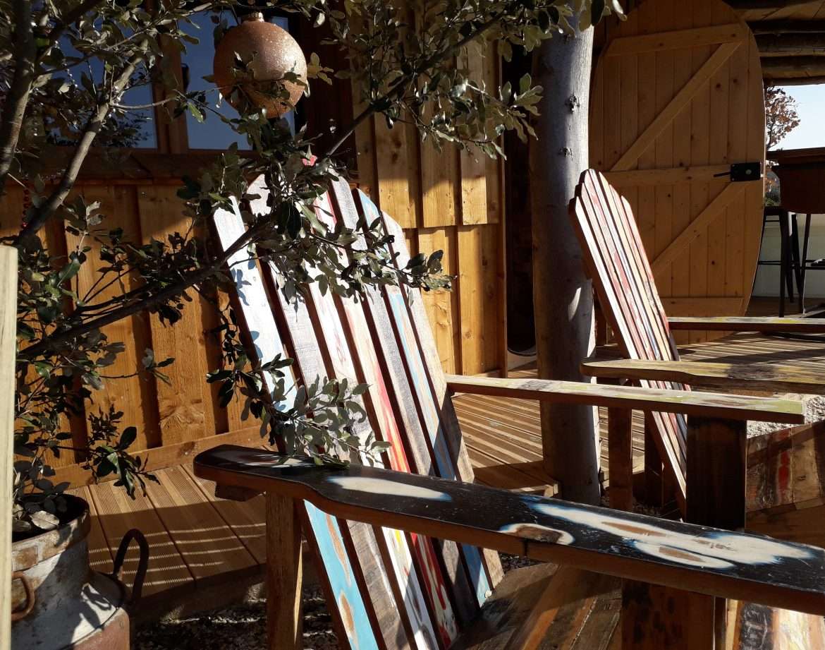 Hébergement insolite en bois avec chaises colorées et ambiance chaleureuse à Languedoc-Roussillon.