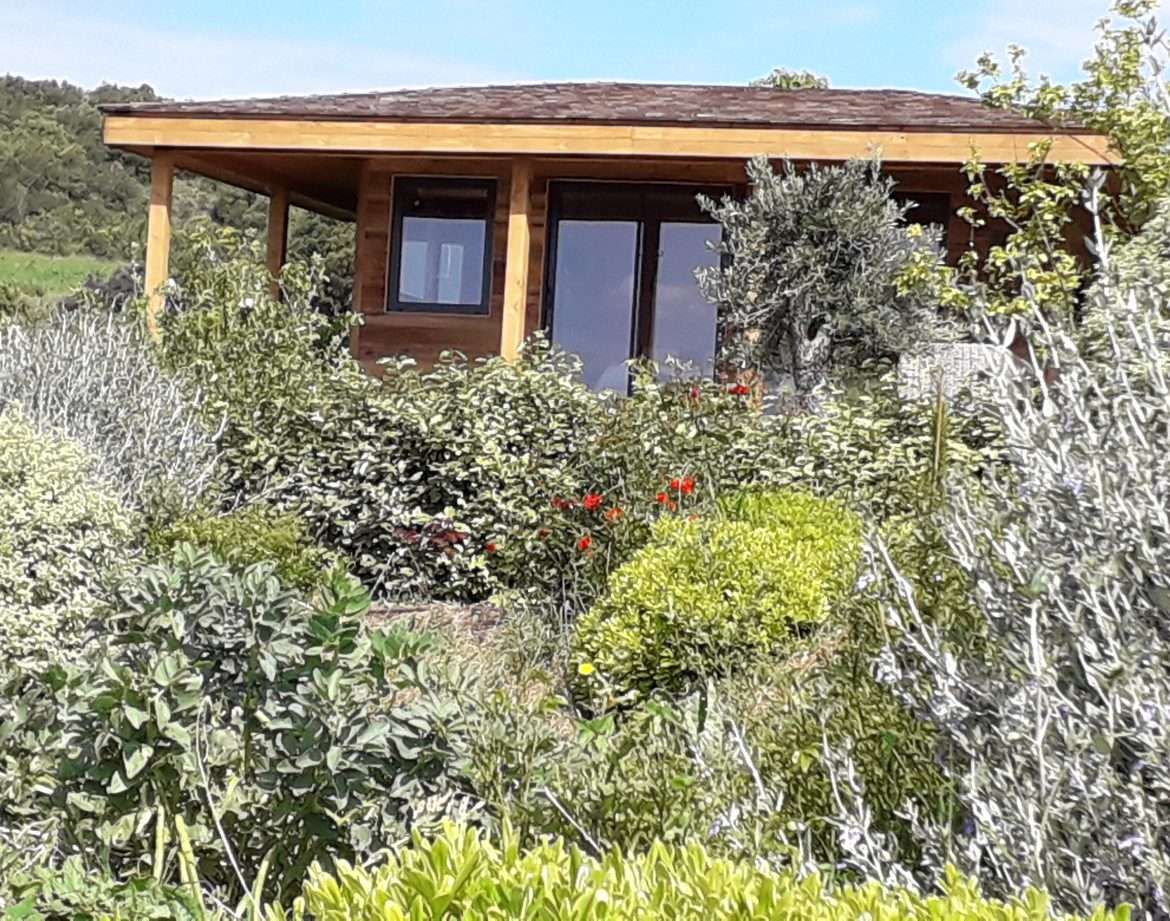 Cabane en bois entourée de verdure et de fleurs colorées à Languedoc-Roussillon.