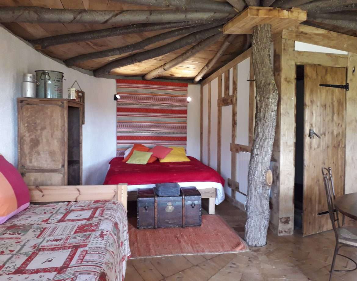 Chalet en bois avec un lit douillet et des touches colorées sur les coussins.