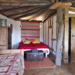 Chalet en bois avec un lit douillet et des touches colorées sur les coussins.