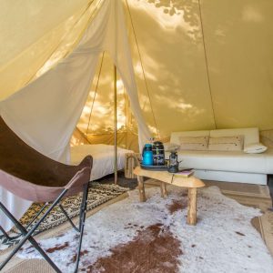 Tente glamping à Midi-Pyrénées, avec canapé confortable et décoration naturelle.