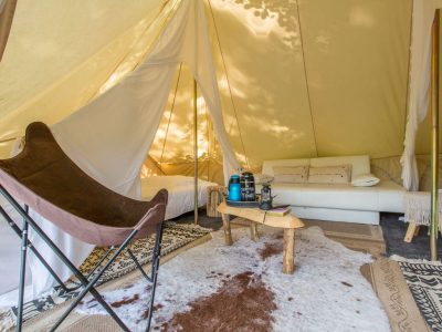 Tente glamping à Midi-Pyrénées, avec canapé confortable et décoration naturelle.