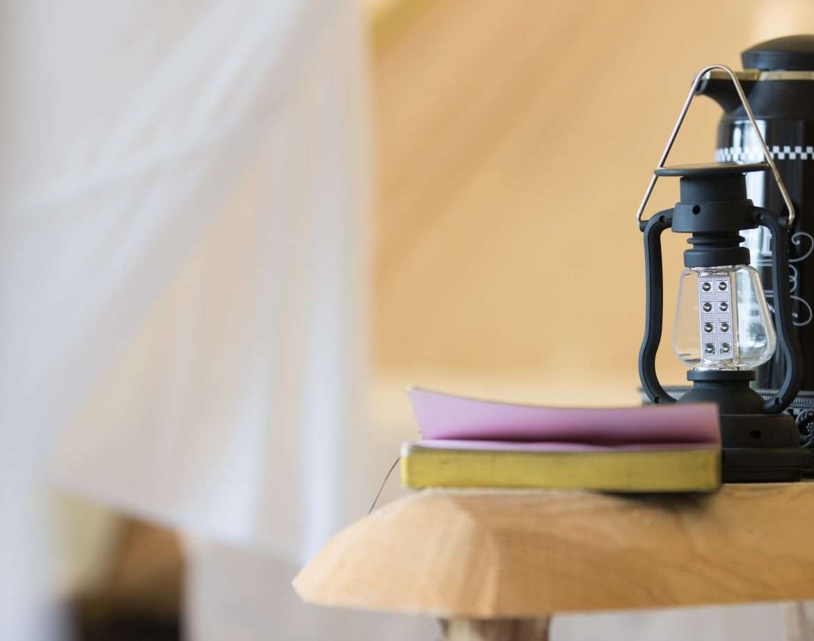Hébergement insolite en Midi-Pyrénées : une tente avec une lampe à huile et un livre sur une table.