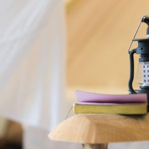 Hébergement insolite en Midi-Pyrénées : une tente avec une lampe à huile et un livre sur une table.