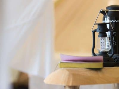 Hébergement insolite en Midi-Pyrénées : une tente avec une lampe à huile et un livre sur une table.