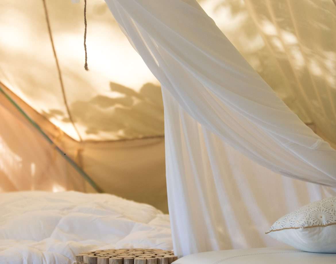 Tente glamping en Midi-Pyrénées, avec un lit douillet et des décorations en bois.