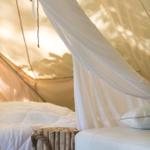 Tente glamping en Midi-Pyrénées, avec un lit douillet et des décorations en bois.