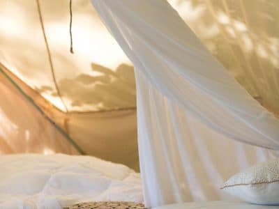 Tente glamping en Midi-Pyrénées, avec un lit douillet et des décorations en bois.