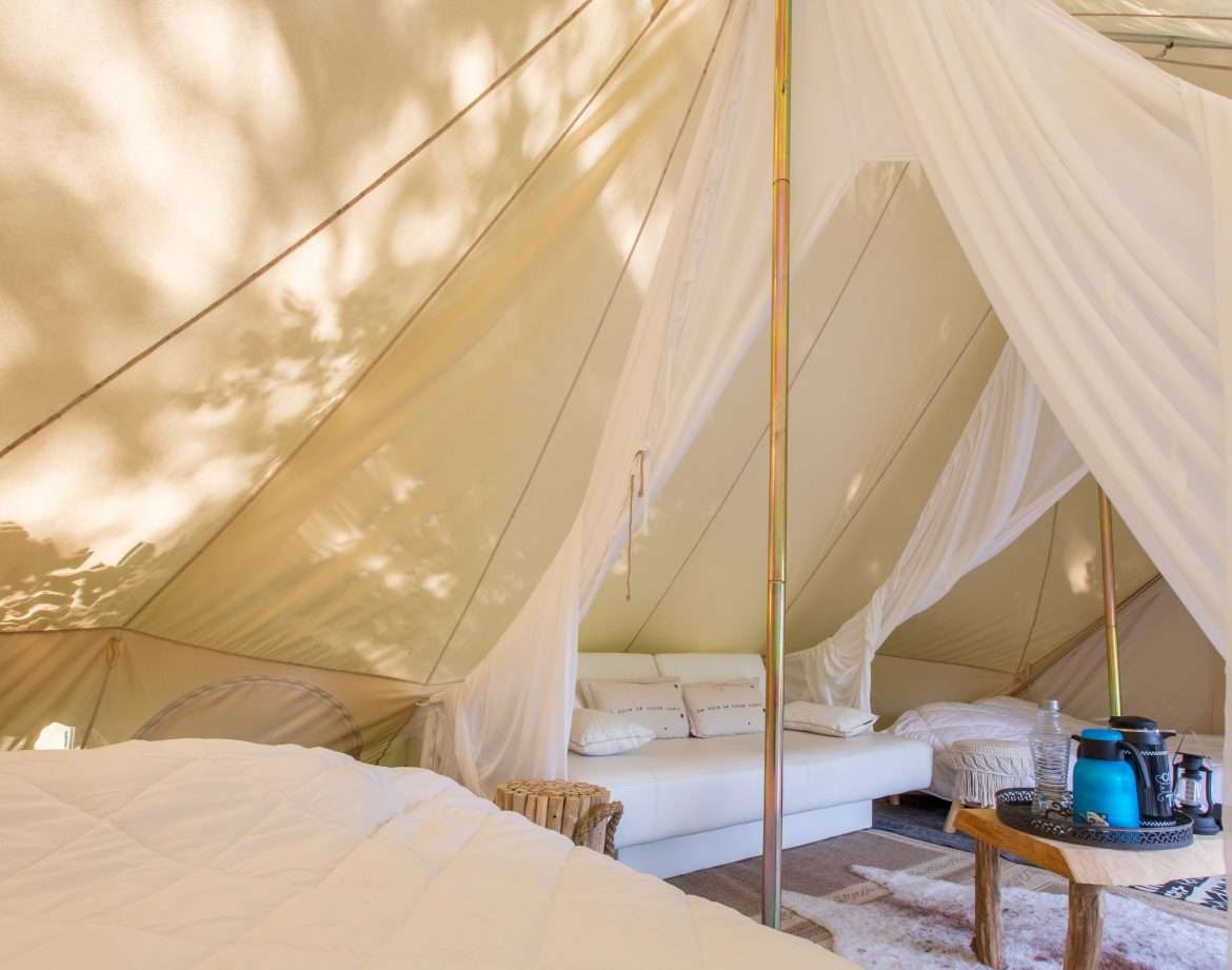 Tente glamping spacieuse avec lit confortable et coin salon cosy.