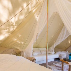 Tente glamping spacieuse avec lit confortable et coin salon cosy.