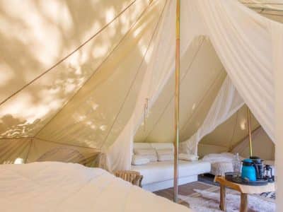 Tente glamping spacieuse avec lit confortable et coin salon cosy.