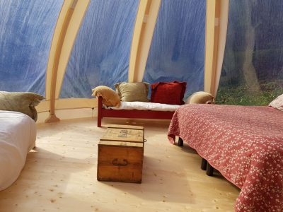 Hébergement insolite en Auvergne-Rhône-Alpes, intérieur lumineux avec lits et coffre en bois.