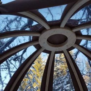 Dôme en bois avec un plafond vitré, offrant une vue sur la nature enneigée.