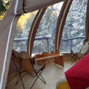 Hébergement insolite en bulle, intérieur chaleureux avec vue sur la neige.