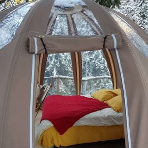 Tente bulle cosy en pleine nature, avec un lit douillet et vue sur la neige.