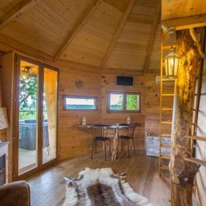Cabane en bois chaleureuse avec vue panoramique et coin salon confortable.