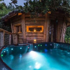 Cabane en bois avec jacuzzi lumineux, nichée dans la verdure à Midi-Pyrénées.