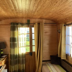 Intérieur chaleureux dun hébergement insolite en bois, avec lumière naturelle et rideaux colorés.