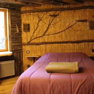 Chalet en bois à Nouvelle-Aquitaine, avec un mur en bambou et un lit douillet.