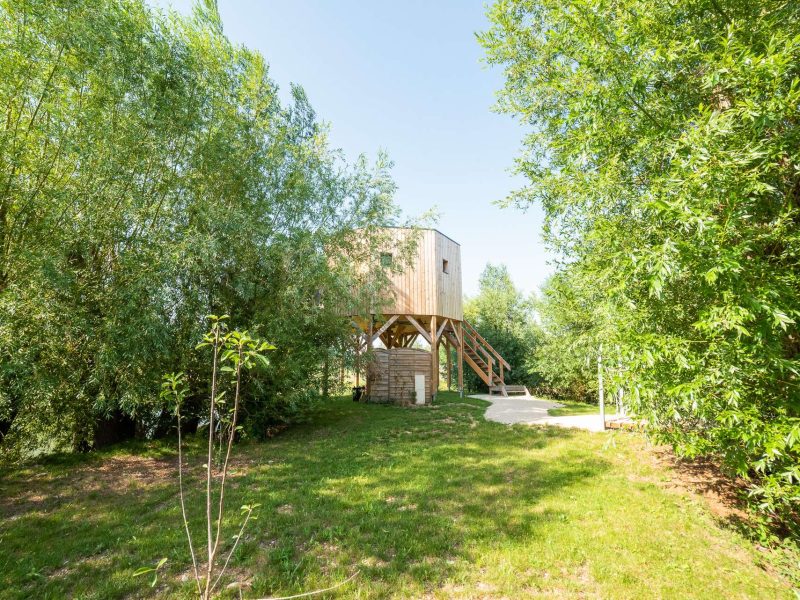 Cabane perchée en bois entourée darbres, offrant un cadre naturel apaisant.