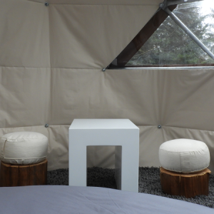 Espace cocooning dans une bulle transparente, avec table et sièges en bois.