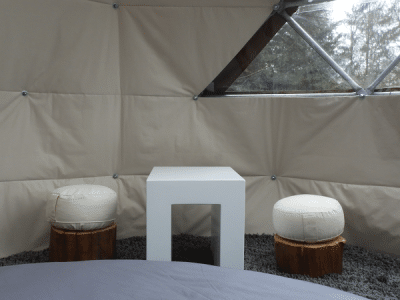 Espace cocooning dans une bulle transparente, avec table et sièges en bois.