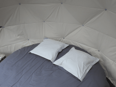 Dôme cosy à Grand-Est, avec un lit rond et des coussins moelleux.