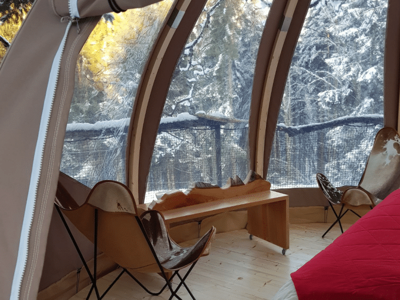 Hébergement insolite en bulle avec vue sur la neige et mobilier en bois chaleureux.