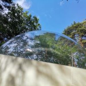 Bulle transparente en pleine nature, offrant une vue imprenable sur le ciel azur.