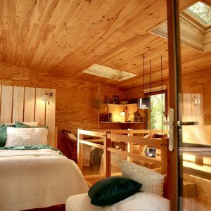 Cabane en bois avec un intérieur chaleureux et lumineux, vue sur la nature.
