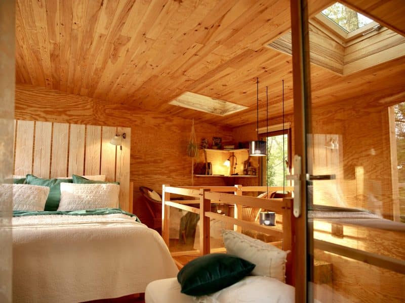 Cabane en bois avec un intérieur chaleureux et lumineux, vue sur la nature.