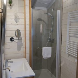 Salle de bain moderne dun hébergement insolite en Aquitaine, avec douche vitrée.
