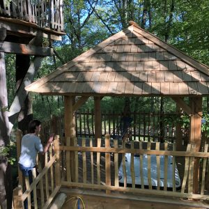 Cabane dans les arbres en Aquitaine, avec un toit en bois et vue sur la forêt.