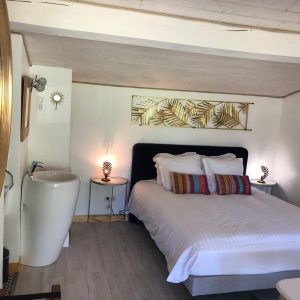 Chambre cocooning en hébergement insolite, décorée de motifs tropicaux et lumineuse.