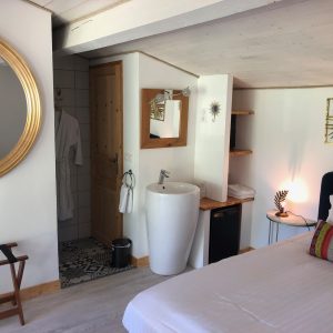 Chambre cosy dans un hébergement insolite en Aquitaine, avec miroir doré et salle de bain moderne.