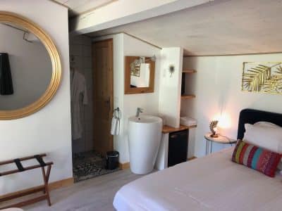 Chambre cosy dans un hébergement insolite en Aquitaine, avec miroir doré et salle de bain moderne.