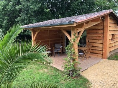 Cabane en bois à Aquitaine, avec terrasse et mobilier extérieur accueillant.