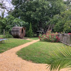 Hébergement insolite en Aquitaine : un tonneau en bois dans un jardin verdoyant.