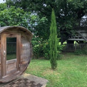 Hébergement insolite en forme de tonneau, entouré de verdure luxuriante.