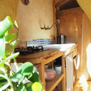 Hébergement insolite en Bretagne : cuisine en bois avec carrelage bleu et plantes vertes.