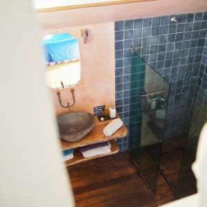 Salle de bain dun hébergement insolite en Bretagne, avec un lavabo en pierre et carrelage.