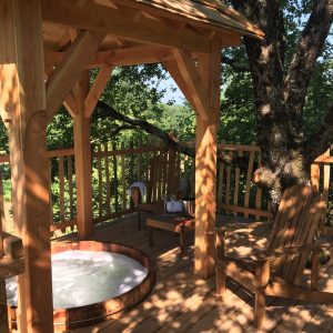 Cabane perchée en Aquitaine avec jacuzzi en bois et vue sur la nature.