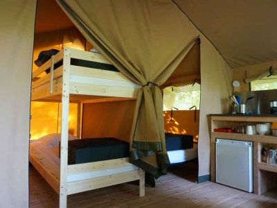 Tente safari confortable avec lits superposés et kitchenette, idéale pour un séjour insolite.