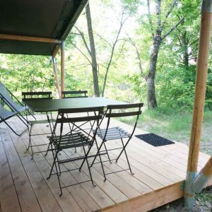 Tente safari en Languedoc-Roussillon avec terrasse en bois et chaises confortables.